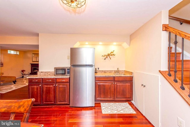 kitchen with light stone countertops, dark wood-style floors, appliances with stainless steel finishes, and a sink