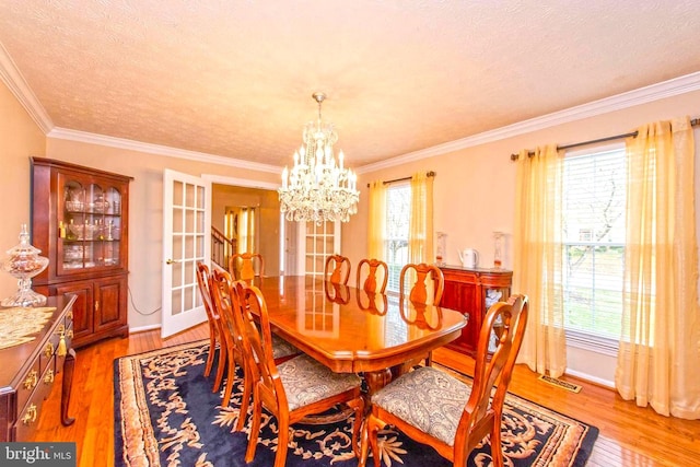 dining space with crown molding, plenty of natural light, visible vents, and light wood-style floors