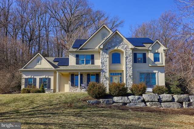 view of front of property featuring a porch, a front yard, and solar panels