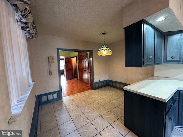 kitchen with pendant lighting, light tile patterned flooring, and a textured ceiling