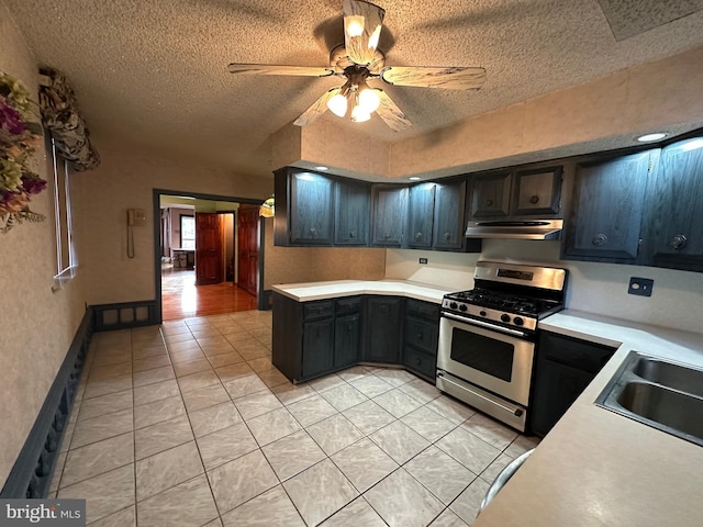 kitchen featuring stainless steel range with gas cooktop, sink, light tile patterned floors, and a textured ceiling