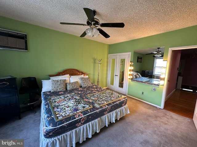 carpeted bedroom with ceiling fan, a wall mounted air conditioner, a textured ceiling, and french doors