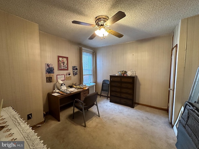 carpeted home office with ceiling fan and a textured ceiling