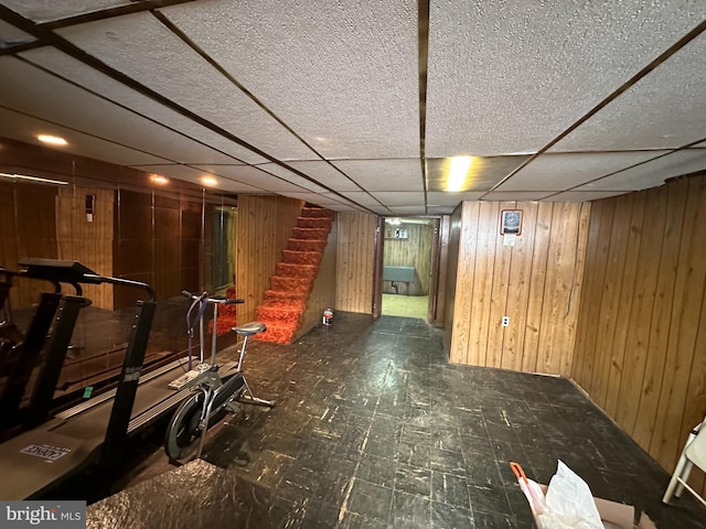 exercise area featuring a paneled ceiling and wooden walls