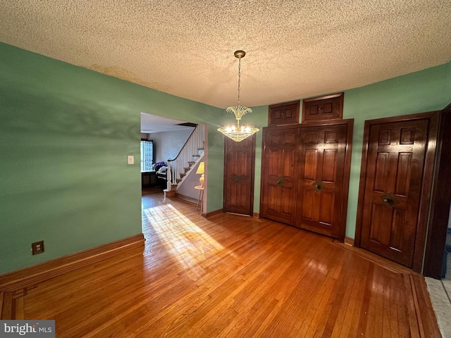 unfurnished dining area with a chandelier, light hardwood / wood-style flooring, and a textured ceiling