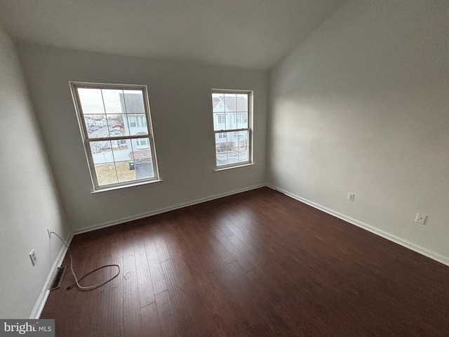 unfurnished room featuring dark hardwood / wood-style floors and vaulted ceiling