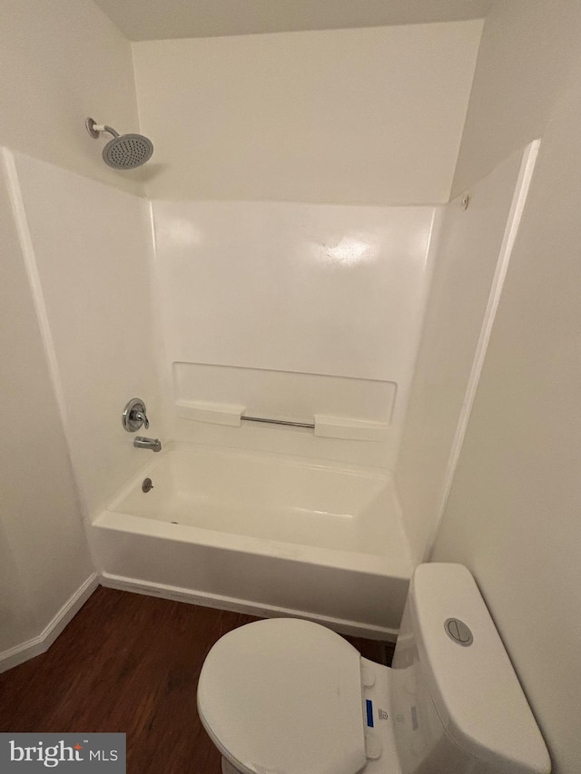 bathroom with hardwood / wood-style flooring, bathing tub / shower combination, and toilet