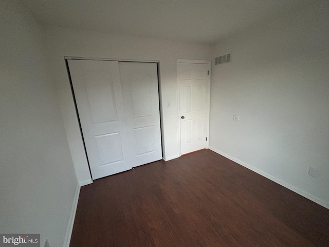 unfurnished bedroom with dark hardwood / wood-style flooring and a closet
