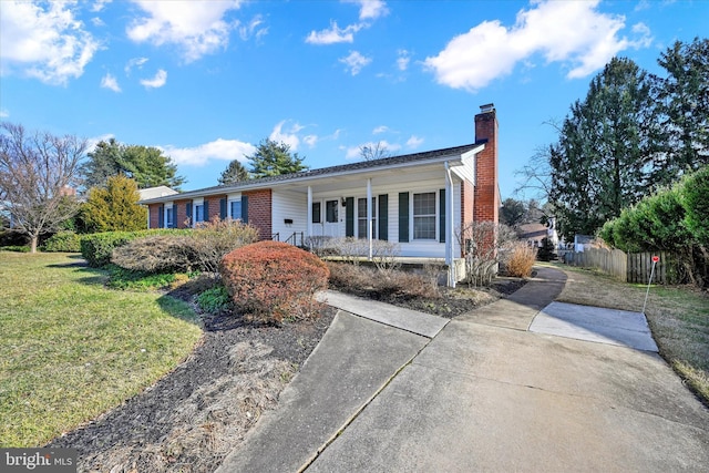 ranch-style house featuring covered porch and a front lawn