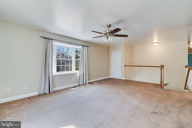 carpeted spare room featuring visible vents, baseboards, and ceiling fan