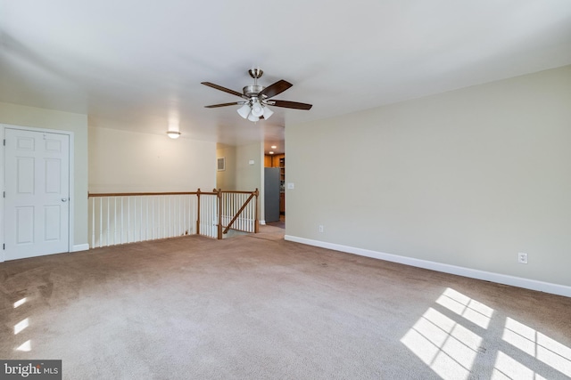 carpeted spare room with ceiling fan and baseboards