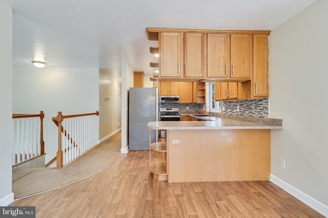 kitchen with open shelves, a sink, light wood-style floors, appliances with stainless steel finishes, and backsplash