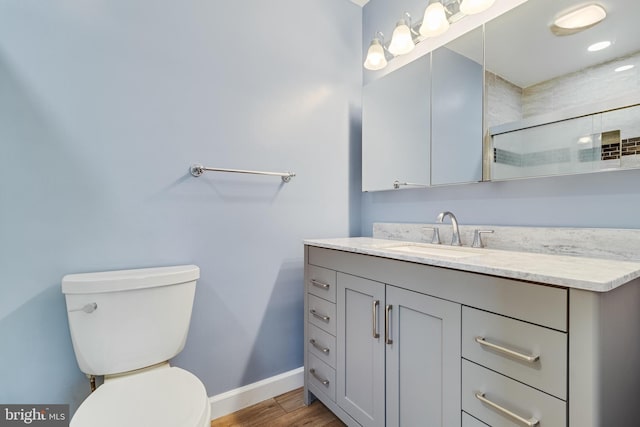 full bath featuring vanity, wood finished floors, a shower with shower door, baseboards, and toilet