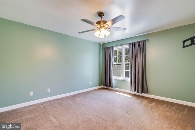 carpeted empty room with a ceiling fan and baseboards