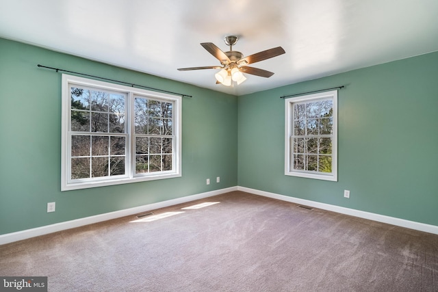 unfurnished room with carpet, a healthy amount of sunlight, and visible vents