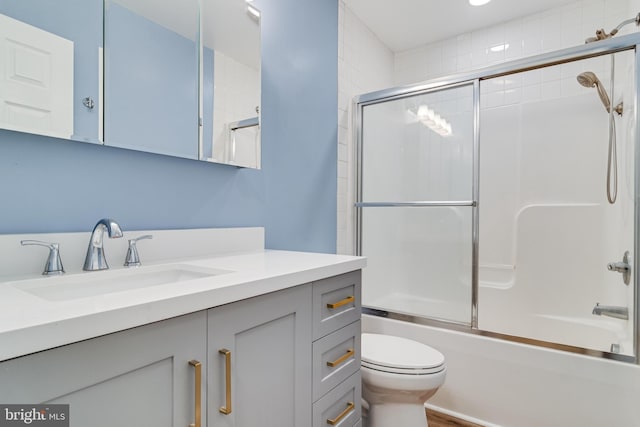 bathroom with bath / shower combo with glass door, vanity, and toilet