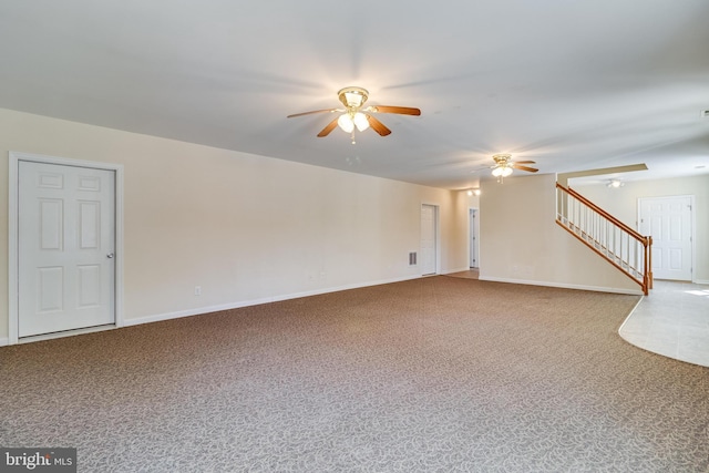 unfurnished living room with carpet flooring, stairway, baseboards, and ceiling fan