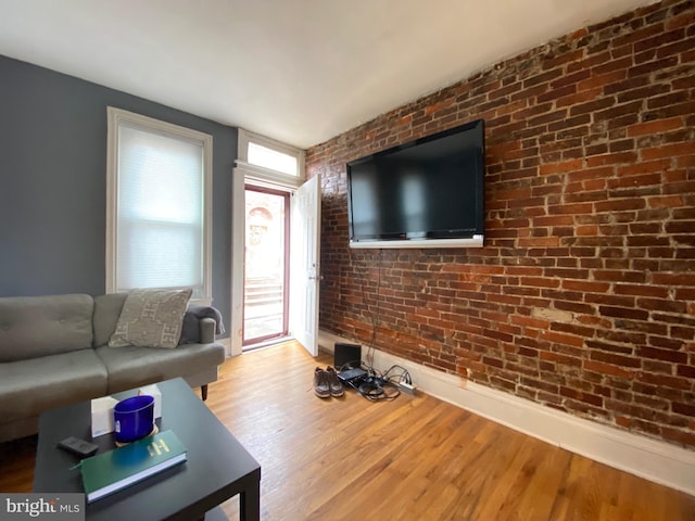 living room featuring brick wall and light wood-type flooring