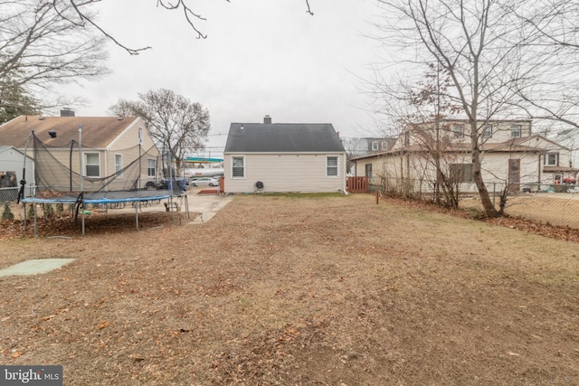 back of house featuring a trampoline and a yard