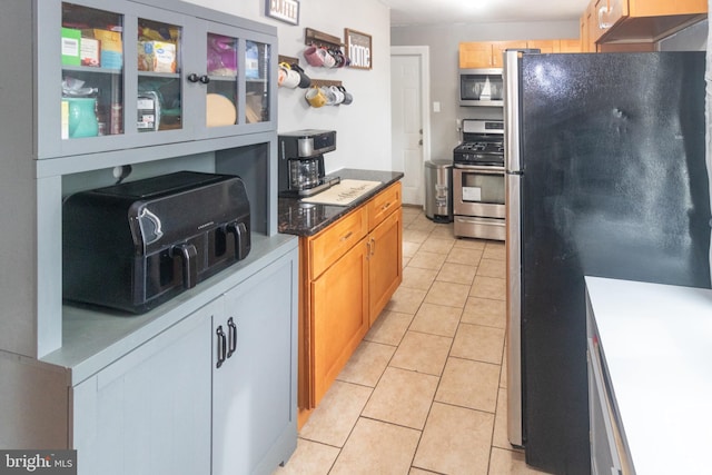 kitchen with appliances with stainless steel finishes, light tile patterned flooring, and light brown cabinets