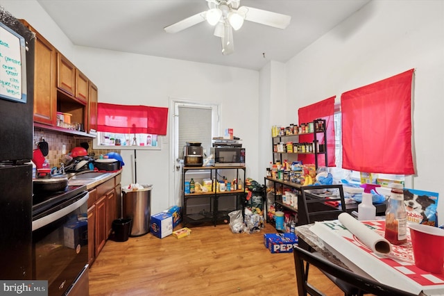 kitchen featuring electric stove, sink, ceiling fan, black fridge, and light wood-type flooring