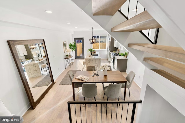 dining room featuring a chandelier, sink, and light wood-type flooring