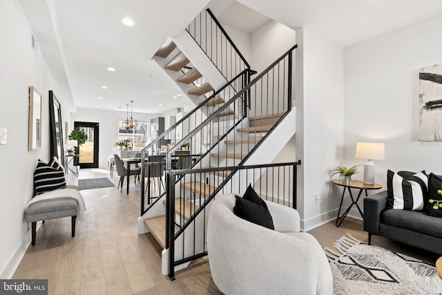 stairway with an inviting chandelier and hardwood / wood-style flooring