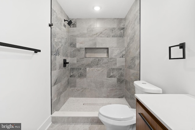 bathroom with vanity, toilet, and tiled shower