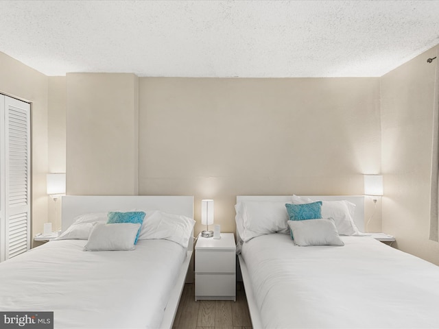 bedroom with a closet, hardwood / wood-style floors, and a textured ceiling