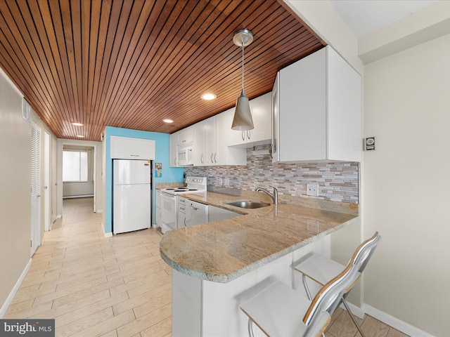 kitchen featuring pendant lighting, sink, white appliances, white cabinets, and kitchen peninsula