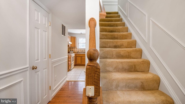 stairs with hardwood / wood-style floors and sink