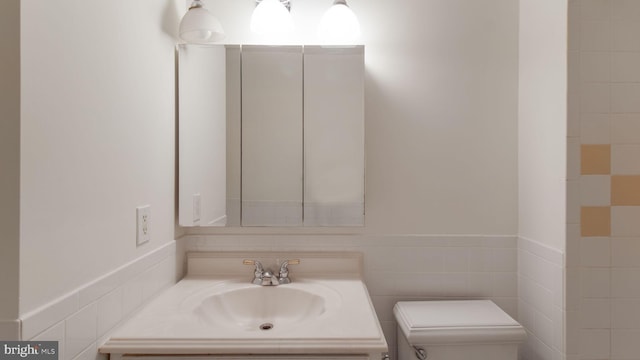 bathroom featuring tile walls, sink, and toilet