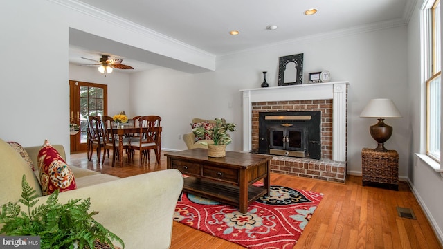 living room featuring hardwood / wood-style floors, crown molding, and a brick fireplace