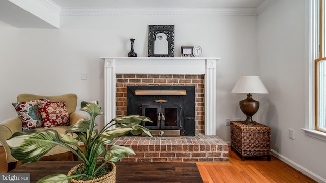 sitting room with a brick fireplace, crown molding, and hardwood / wood-style flooring