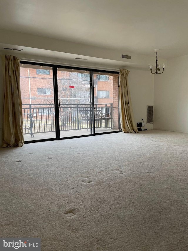 unfurnished room featuring an inviting chandelier, carpet flooring, and a wealth of natural light