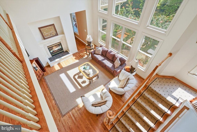 living area with a high end fireplace, a high ceiling, baseboards, and wood finished floors