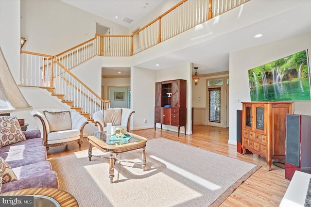 living area with visible vents, stairway, recessed lighting, a towering ceiling, and wood finished floors