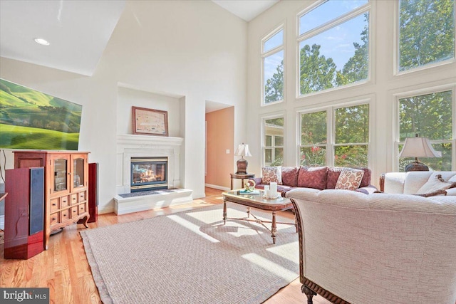 living room featuring recessed lighting, a glass covered fireplace, plenty of natural light, and light wood-style floors