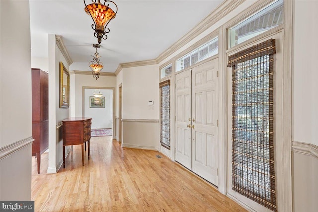 entryway featuring crown molding, light wood-style flooring, and baseboards