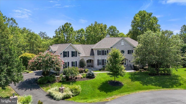 view of front facade featuring a front lawn, stone siding, and driveway