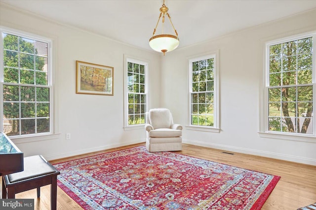 sitting room with visible vents, crown molding, and wood finished floors