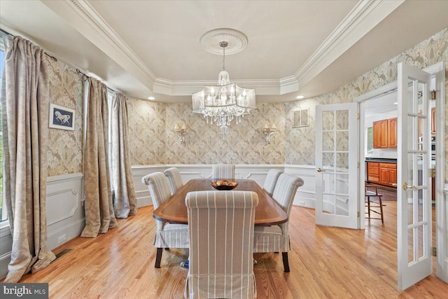 dining room with a raised ceiling, a notable chandelier, crown molding, and wallpapered walls