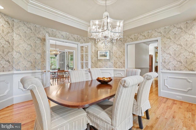 dining area featuring a tray ceiling, a notable chandelier, and wallpapered walls