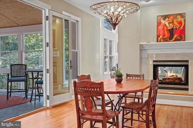 dining space with a multi sided fireplace, an inviting chandelier, and wood finished floors