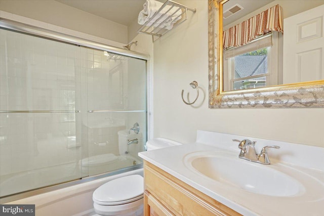 bathroom featuring vanity, toilet, visible vents, and bath / shower combo with glass door