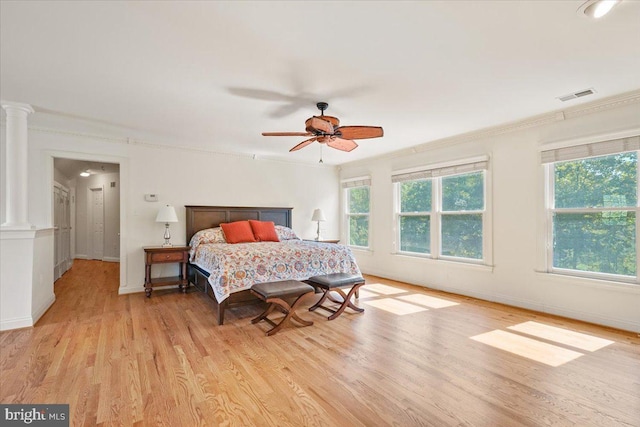 bedroom featuring visible vents, ornamental molding, light wood-style floors, decorative columns, and baseboards