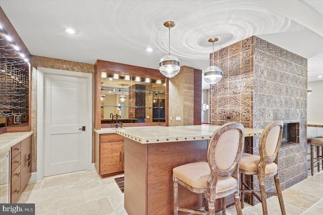 kitchen featuring stone finish flooring, a tile fireplace, a breakfast bar, and light countertops