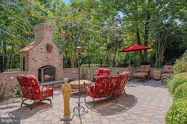 view of patio with an outdoor brick fireplace and fence