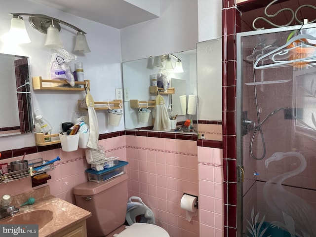 bathroom with vanity, toilet, tile walls, and a shower with shower door