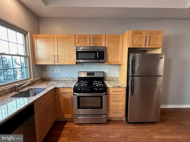 kitchen with stainless steel appliances, sink, light brown cabinets, and light hardwood / wood-style floors